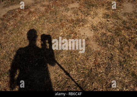 Un ombra di un fotografo e treppiede contro un campo di erba una notte lunga esposizione Foto Stock