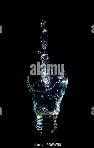 Creative lampadina rotta con fontana di acqua isolato su sfondo nero con flash Foto Stock