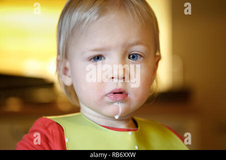 Bambino con latte di baffi da mangiare in modo indipendente, facendo un pasticcio. Lo sviluppo della prima infanzia, le tappe e i progressi, l'esperienza di apprendimento basate Foto Stock