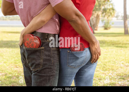 Essi detengono reciprocamente il retro con cioccolato cuori boxed candy in senso opposto tasca. Foto Stock
