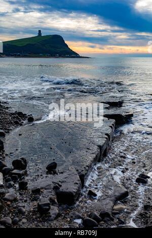 Fotografia del paesaggio in orientamento verticale su Kimmeridge Bay beach dalla battuta di lavaggio che si affacciano sulla torre Clavell sotto cieli drammatici. Foto Stock