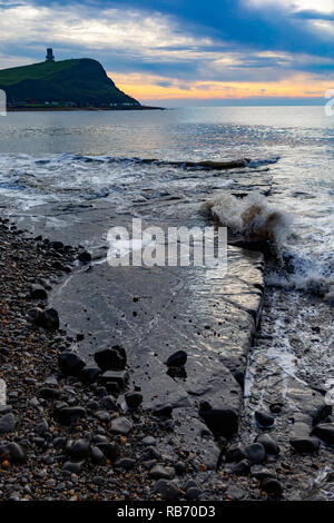 Fotografia del paesaggio in orientamento verticale sulla spiaggia Kimmeridge guardando fuori dopo un lavaggio ledge circondato da ruvida sotto oscillante moody skies. Foto Stock