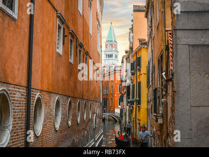 Venezia, Italia - 18 Settembre 2018: due gondolieri portano i turisti sulle gondole in uno stretto canale con la torre campanaria in vista di Venezia, Italia. Foto Stock