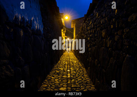 Strada di ciottoli e mura Inca al crepuscolo, Ollantaytambo, Perù Foto Stock