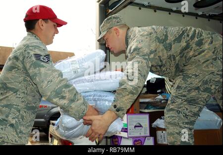 Sulla destra, Senior Airman Igor Karlov, 111disponibilità logistica squadrone tecnico di alimentazione, riceve oggetti donati da un membro della 201st ingegnere rapidamente dispiegabile operativi pesanti squadrone di riparazione Engineer (rosso) cavallo Squadron, det.1, Dicembre 15, 2016 a Horsham aria stazione di guardia, Pa. Il 111parafango attacco ha Donati giocattoli e altri elementi a un locale per la cura dei vostri bambini facility per oltre due decenni. Foto Stock