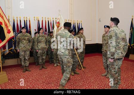 Il cap. Olufemi O. Apata, centro, comandante in entrata della sede centrale e sede di distacco, U.S. Presidio militare di Ansbach, passa la sua unità guidon torna a Sgt. 1. Classe Alvin bianco, distacco sergente, durante un cambio del comando cerimonia per l'unità 6 dicembre 2016, presso il Von Steuben centro comunitario in Ansbach, Germania. Foto Stock