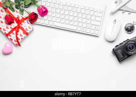 San Valentino il concetto di viaggio, notebook, fotocamera, rose fiori confezione regalo, tastiera e mouse wireless su sfondo bianco. Foto Stock