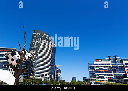 La vacca su un albero di una scultura in Melbourne Docklands.Il punto di Victoria Apartments e National Australia Bank con sede in background Foto Stock