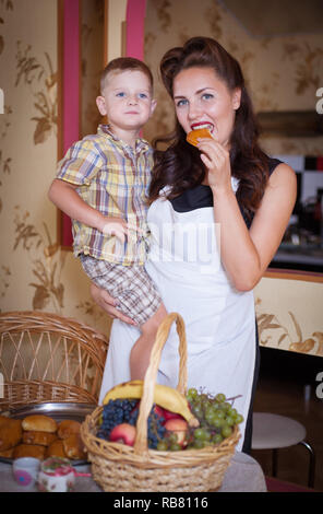 Madre e figlio in cucina con la pasticceria di altri cibi. Studio shot, arredamento. Foto Stock