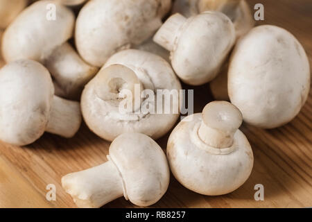 Saporiti funghi su un tavolo di legno. Funghi in cucina su un tagliere. Sfondo luminoso. Il fuoco selettivo Foto Stock