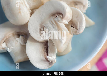 Gli champignon tagliati a fettine, close-up, su una piastra di blu, il fuoco selettivo Foto Stock