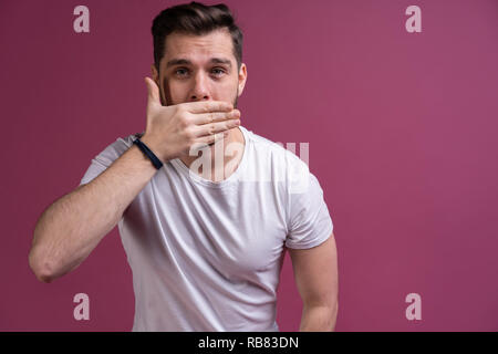 Ho paura. Spavento. Paura l'uomo. Business man standing isolata sulla tendenza rosa di sfondo per studio. Le emozioni umane, espressione facciale concetto. Foto Stock