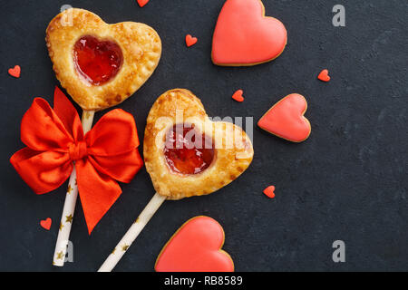 San Valentino a forma di cuore torta alle fragole pop o torta appare su sfondo nero. Vacanza il concetto di vendita. Foto Stock