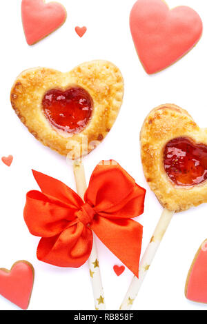 A forma di cuore la torta di fragole pops, rosso smaltato cookie e caramelle per il giorno di San Valentino. Isolato. Foto Stock