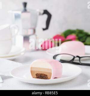 Mousse alla moda di torte con specchio rosa smalto. A forma di cuore ad tratta per il giorno di San Valentino. Fiori in background. Foto Stock