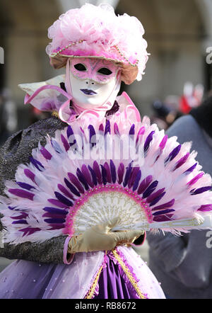 Venezia, VE, Italia - 5 Febbraio 2018: Donna con ventola del palmare e maschera bianca durante il carnevale Foto Stock
