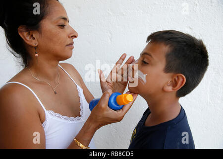 Madre di mettere la protezione solare Crema sul suo figlio il suo volto nel Salento, Italia. Foto Stock