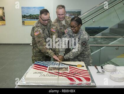 Seguendo la tradizione, Briga. Gen. Phillip S. Jolly, U.S. Esercito dell'Europa il vice comandante generale di mobilitazione e di affari di riserva, taglia la torta con il più giovane e più anziano membro dell'organizzazione durante la 380 Guardia Nazionale celebrazione di compleanno su argilla Kaserne, Wiesbaden, Germania, 13 dicembre 2016. Nella foto da sinistra a destra sono Master Sgt. Keith Knudson, Oltremare di implementazione del programma di formazione sottufficiale; Jolly; e Sgt. Helen Buford, intelligence analyst presso U.S. Presidio militare di Wiesbaden. Foto Stock