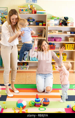 Gruppo di bambini i bambini giocando con colorati giocattoli educativi insieme con le madri in vivaio sala giochi Foto Stock