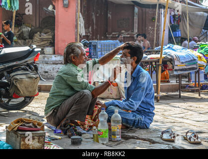 Jodhpur, India - Novembre 6, 2017. Un uomo riceve una barba a una strada barbiere di Jodhpur, India. Jodhpur è la seconda più grande città nello stato del Rajasthan. Foto Stock