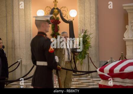 Un uomo saluta il scrigno del Sen. John H. Glenn, Jr., durante una visualizzazione pubblico all'Ohio Statehouse, Columbus, Ohio, a Dic. 16, 2016. Dopo aver volato 149 missioni di combattimento della Seconda Guerra Mondiale e la guerra di Corea, Glenn divenne il primo americano in orbita attorno alla terra nel 1962. Dopo essersi ritirato dal programma spaziale, Glenn era stato eletto per gli Stati Uniti Senato nel 1974 per rappresentare lo stato dell'Ohio. Foto Stock