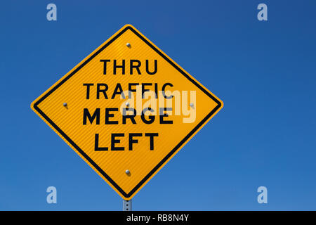 Il 'traffico passante Immettersi a sinistra' street sign in il sole della California. Foto Stock