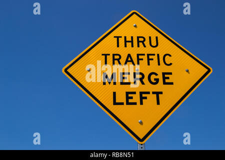 Il 'traffico passante Immettersi a sinistra' street sign in il sole della California. Foto Stock