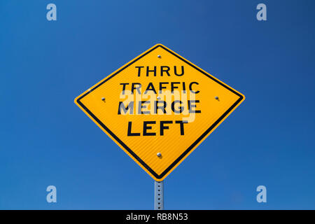 Il 'traffico passante Immettersi a sinistra' street sign in il sole della California. Foto Stock