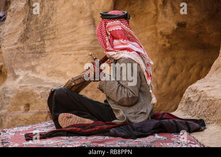 Il vecchio beduino nel keffiyeh gioca sulla nazionale lo strumento musicale di Giordania,Petra, Giordania Foto Stock