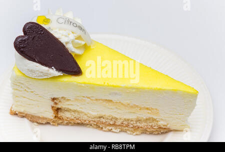 Limone cheese cake con cuore di cioccolato servito su una piastra bianca, marcato con la parola olandese per il limone Foto Stock