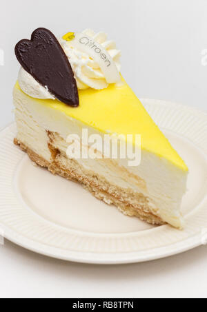 Limone cheese cake con cuore di cioccolato servito su una piastra bianca, marcato con la parola olandese per il limone Foto Stock