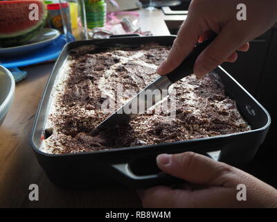 Casa mia moglie il taglio e la preparazione di tiramisù. Foto Stock