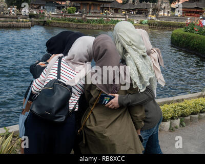 Ragazze musulmane prendendo un selfie al Ulun Danu Beratan in Bali. Foto Stock