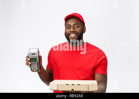 Felice giovane Africano Americano uomo consegna tenendo in mano una carta elettronica di macchina di pagamento e consegna prodotto. Isolate su uno sfondo grigio Foto Stock