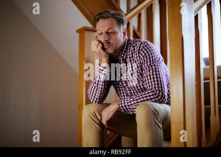 Uomo seduto sulle scale riflessivo Foto Stock