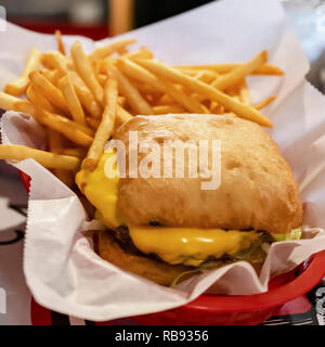 Il cibo da bar: hamburger grigliati con bun e frys in un cestello. Foto Stock