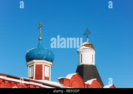 Belle cupole con croci d'oro oltre le mura in Russia contro il blu cielo chiaro. Foto Stock