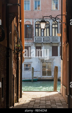 Strada stretta con la vecchia lanterna e visualizzare il canale laterale a Venezia, Italia Foto Stock