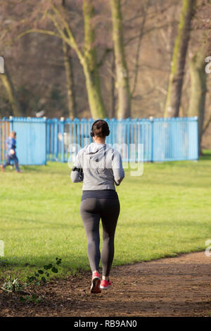 Kidderminster, Regno Unito. 8th gennaio 2019. Tempo nel Regno Unito: Il primo sole per un po' vede i jogging nel parco a partire dal loro regime fitness del 2019. Una runner femminile con cuffie, vista posteriore, ascolta la musica mentre attraversa il parco godendo il suo regime di esercizio. Credito: Lee Hudson/Alamy Live News Foto Stock