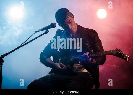 Focalizzato musicista maschio giocando sulla chitarra elettrica vicino al microfono sul palco durante un concerto rock Foto Stock