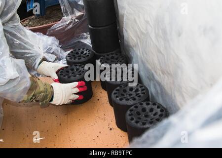 DONGDUCHEON, Repubblica di Corea - un soldato con 3° Battaglione, campo xiii reggimento di artiglieria, 210th campo brigata di artiglieria, posiziona un blocco di carbone su un foglio di legno per una famiglia in città Dongducheon dic. 21. Il 210th FAB fornito questo servizio come uno sforzo congiunto con Gyeonngi Provincia e ha consegnato 5.000 blocchi di carbone per sostenere le famiglie durante tutta la stagione invernale. Foto Stock