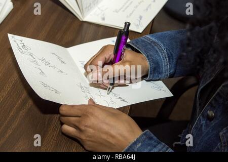 Airman Miranda Loera, 4° Fighter Wing Public Affairs fotoreporter, segni di cartoline in Goldsboro, North Carolina, prima di uscire per visitare con i residenti del North Carolina State veterani Home in Kinston, North Carolina, Dic 24, 2016. Circa 45 volontari da Seymour Johnson Air Force Base, Goldsboro Elk Lodge #139 e Wayne County passata fuori a mano goody borse e carte di Natale per i veterani durante la vacanza visita. Foto Stock