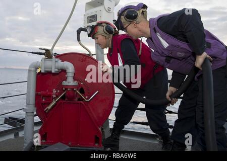 Mare Mediterraneo (dec. n. 27, 2016) macchinista compagno del 3° di classe Andrea Delagarza, a sinistra e a turbina a gas tecnico dei sistemi di allarme antincendio meccanica Jordan Ford, destro, fissare un tubo flessibile di incendio durante la simulazione di una air craft trapano crash a bordo del Arleigh Burke-class guidato-missile destroyer USS Cole (DDG 67). Cole sta conducendo operazioni navali negli Stati Uniti Sesta flotta area di operazioni a sostegno degli Stati Uniti per gli interessi di sicurezza nazionali in Europa. Foto Stock