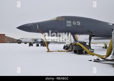 Giallo aria condizionata tendere i tubi flessibili dal lato inferiore di un B-1B Lancer di una grande unità di riscaldamento come lavori di manutenzione su aeromobili continua nonostante l'accumulo di neve in Oklahoma City Air Logistics complesso Gennaio 6, 2017, Tinker Air Force Base in Oklahoma. Notevole nevicata che si è verificata durante la notte e nelle prime ore del mattino del 6 gennaio in Oklahoma City regione ma non fermò le operazioni di manutenzione al tentacolare di base. Foto Stock