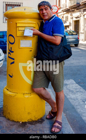 Gli uomini di poke una lettera in una cassetta postale in Spagna Foto Stock