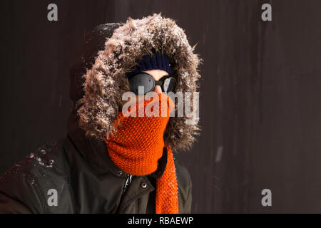 Ritratto di un singolo maschio avventuriero invernali indossando un caldo manto verde con cappa di pelliccia, un blu berretto da sci, un foulard arancione e nero in stile retrò gli occhiali di protezione Foto Stock