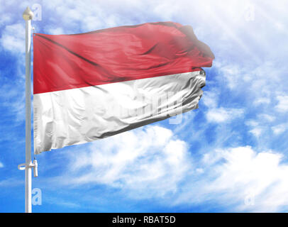 Bandiera nazionale dell'Indonesia su un pennone di fronte blu cielo. Foto Stock