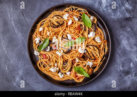 La pasta alla norma - cibo tradizionale italiano con melanzane, pomodoro, formaggio e basilico, vista dall'alto. Foto Stock