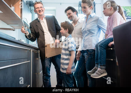 Venditore di famiglia che mostra le caratteristiche di una nuova cucina Foto Stock