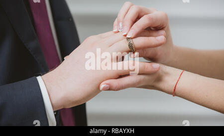 Sposa di mettere un anello di nozze su stallieri dito. Foto Stock